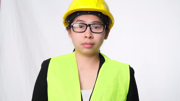 Woman technician smiling with helmet and showing a heart shape with hands on white background. alt