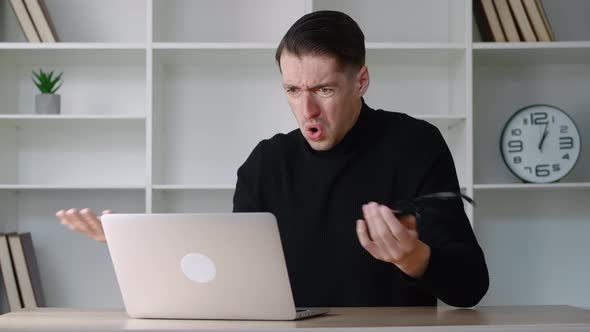 Portrait of Shocked Male Businessman Looking at Laptop Takes Off Glasses and Say What alt
