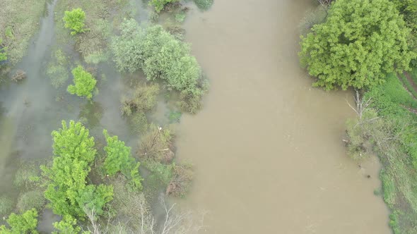 Descending over the flooded coastal area of narrow river 4K aerial video alt