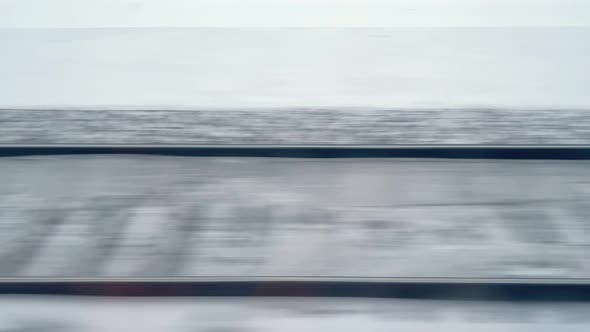View in Winter of the Railway in the Snow Through Train Window Moving Fast Motion Blur Rails