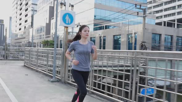 Beautiful young Asian woman athlete running in the city.