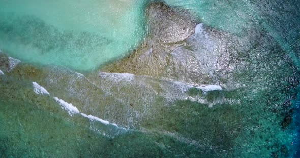 Daytime drone copy space shot of a sandy white paradise beach and aqua blue water background in best alt