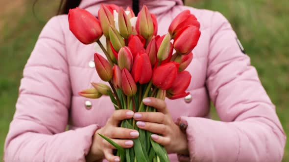 Beautiful young woman holding a bouquet of wildflowers red tulips. Close-up bouquet