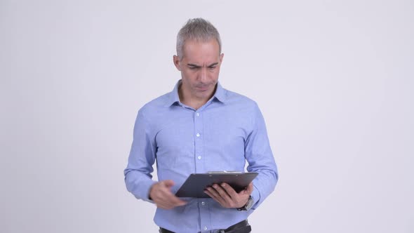 Stressed Persian Businessman Showing Clipboard and Giving Thumbs Down alt