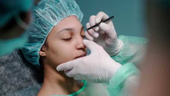 Surgeon Examines Girl's Face Before Rhinoplasty Surgery Drawing on Her Face