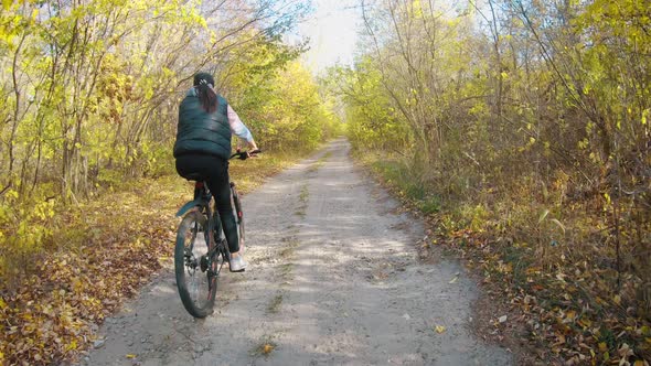 Woman Cyclist Riding Mountain Bike. Cycling Along the Forest Road on Sunny Day. Adventure Lifestyle alt