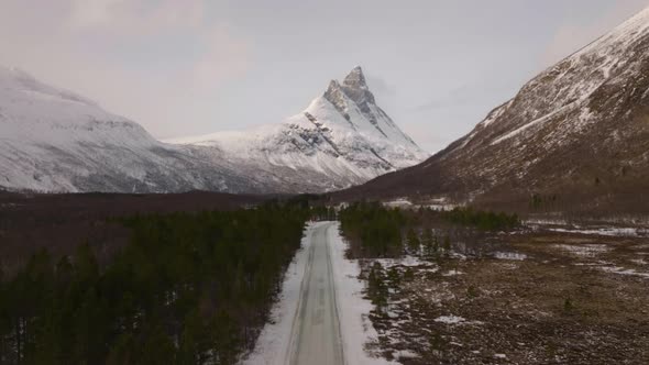 Winter road leading straight to Otertinden mountain in northern Norway. 4K aerial straight ascent d alt