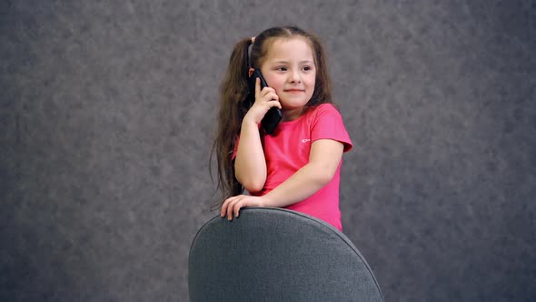 Little girl talking on phone. Portrait of little positive girl talking on cell phone alt