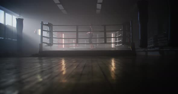Young Woman Boxer With Her Hands Wrapped in Bandage Jumping on Rope in Dark Ring Space a Gym with alt