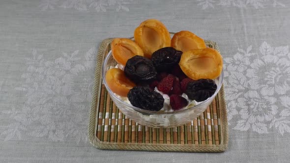A Bowl of Cottage Cheese and Apricots Raspberries and Prunes on Top