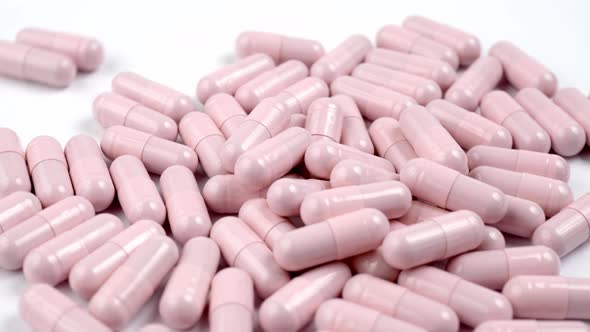 Close up of the rotation soft pink pills or capsules on white background alt