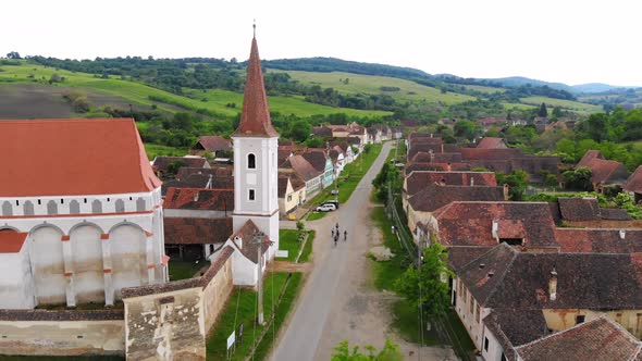 Group of friends on bicycles, riding through the village close to the church tower on a country road alt