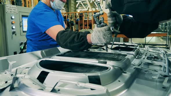Car Manufacturing Workers Using Structural Adhesive at a Car Factory alt