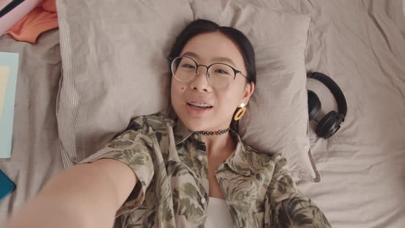 POV of Asian Gen Z Girl Recording Video Blog from Bed alt