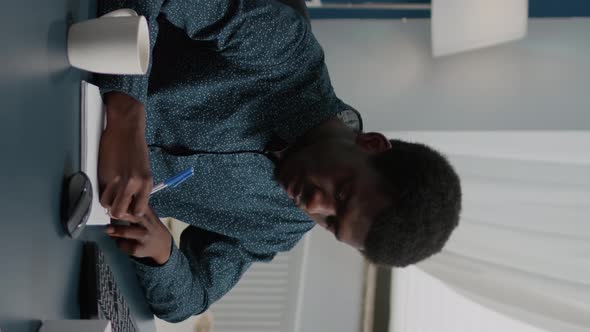 Vertical Video Freelancer Taking Notes on Notepad and Looking Into Computer alt