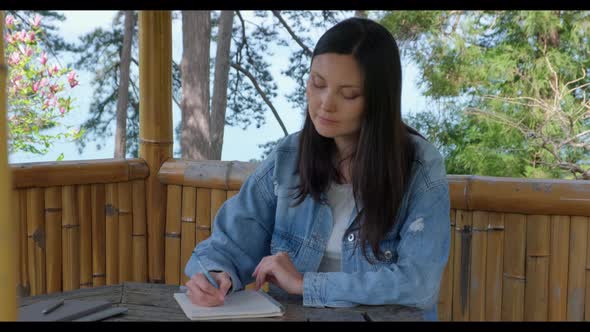 Woman Writing at Notebook in the Garden