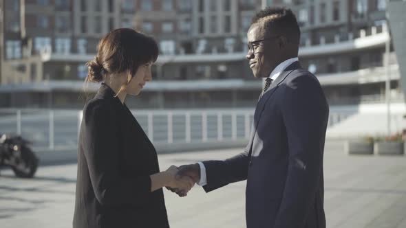 Side View of Multiracial Partners Shaking Hands on Sunny City Street. Handshake of Confident alt