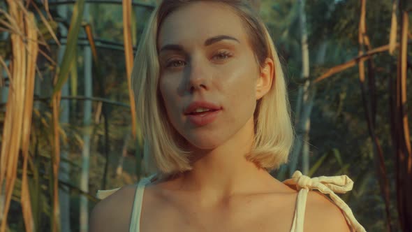 Young Blonde Standing Contemplating Tropical Rainforest Sunset Light Coming From Above alt