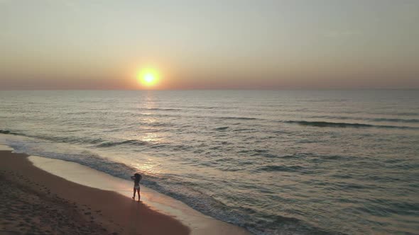 Beautiful Scene of a Woman Walking on Ocean Beach at Sunset.