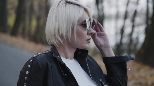 Close Portrait of Blonde Looks Aside and Corrects Sunglasses alt