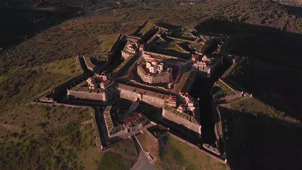 The fort of Nossa Senhora da Graça at sunset with golden light and dark shadows. alt