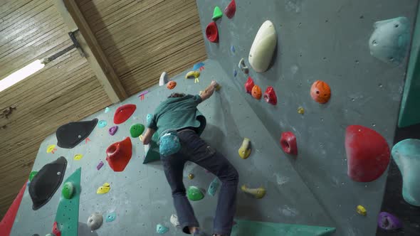 Man Climbs the Wall Training on a Climbing Wall Practicing Rockclimbing Mountaineer Training alt