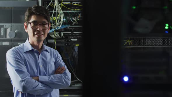 Portrait of smiling asian male it technician by computer server alt