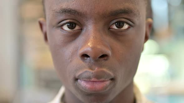 Close Up of Serious Young African Man Looking at Camera alt