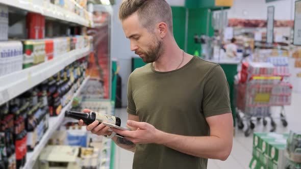 Man is Checking Beer By Application in Smartphone in Supermarket alt