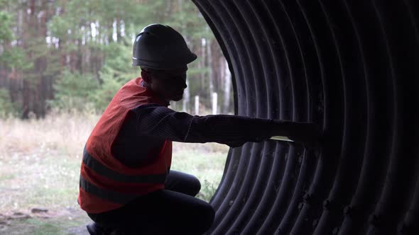 A builder engineer makes measurements of the structure of an underpass under the railway. alt