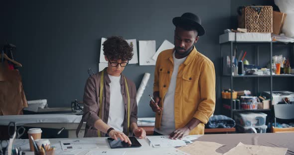 Couple of Tailors Using Tablet Looking at Papers Working in Workshop Together alt