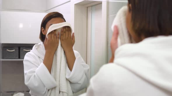 A Young Beautiful Woman Looks in the Mirror and Wipes Her Face with a Towel