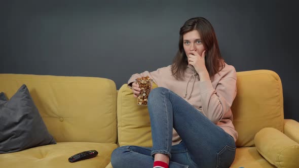 Concentrated Girl Watching Thriller Movie or Horror Film on TV