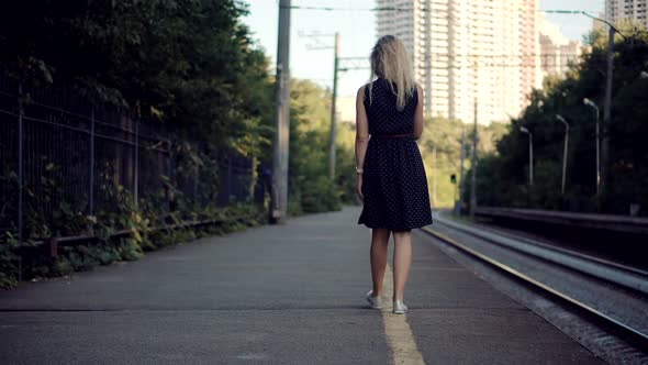 Woman In Dot Dress Walking On Railroad Station Platform. Girl Waiting Train On Public Transport. alt