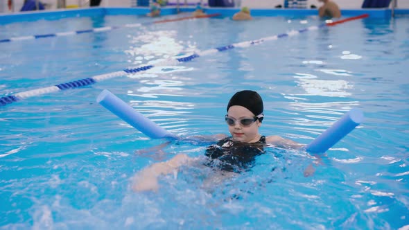Swimming Lessons for Children in the Pool - Beautiful Fair-skinned Girl Swims in the Water
