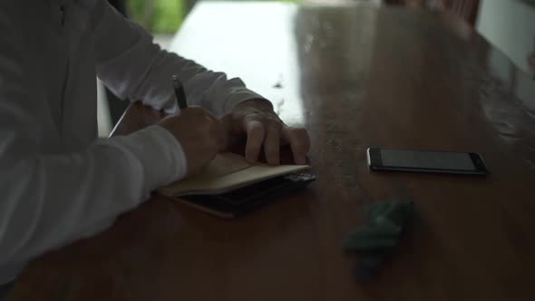 Groom's vow. Male hands write romantic letter in vintage notebook to bride. Accessories. Wedding day alt