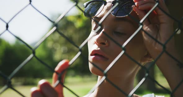Mixed race woman looking through a fence alt