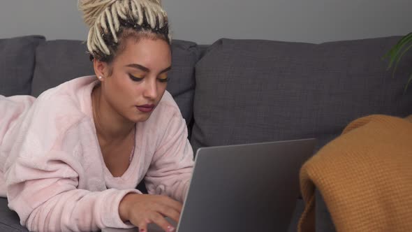 Young Woman Freelancer Working on Laptop While Lying on Sofa at Home alt