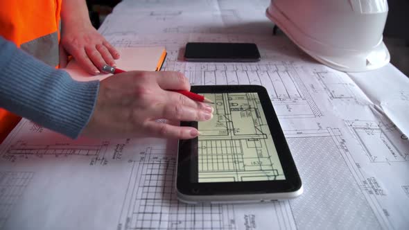 civil engineer working with tablet computer and construction plan on table