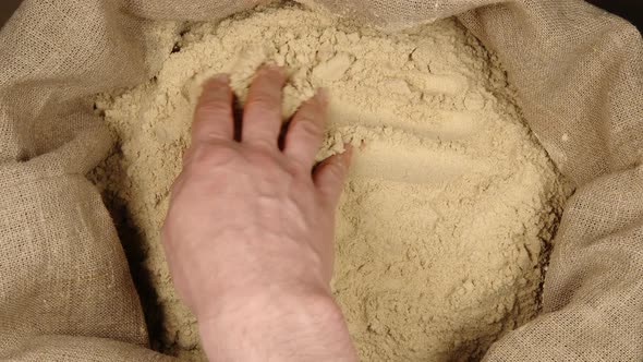 Human hand touching a ginger powder in a sac