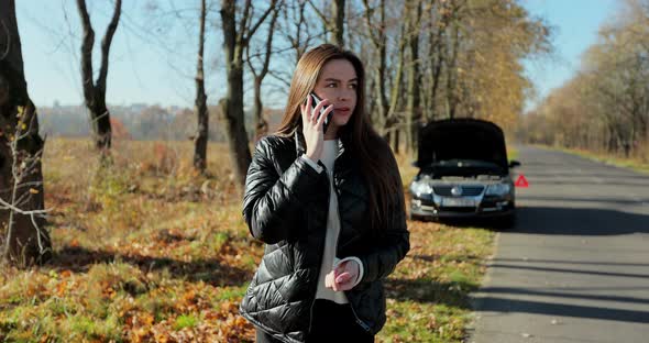 Young Stressed Woman Calling for Assistance with Her Car Broken Down By the Roadside alt