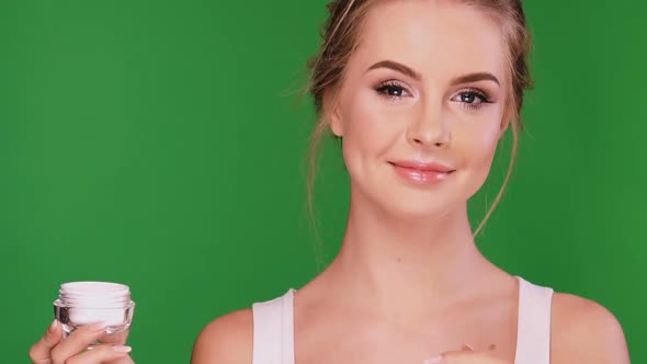 Happy Woman Applies Cream on Neck and Looking To the Camera