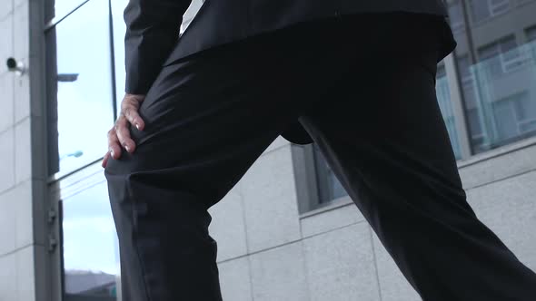 Man in Suit Rubbing Knee Outdoors, Suffering Joint Inflammation, Chronic Disease