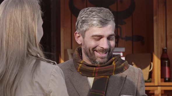 Smiling man brings coffee to girl outdoor coffee shop