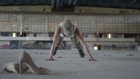 Strong Young Woman in Military Uniform Wringing Herself From the Floor on a Concrete Floor alt