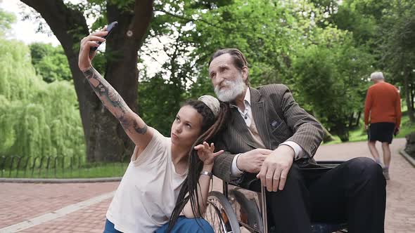 Modern Young Girl with Dreadlocks which Making Selfie Together with Her Handsome Granddad alt