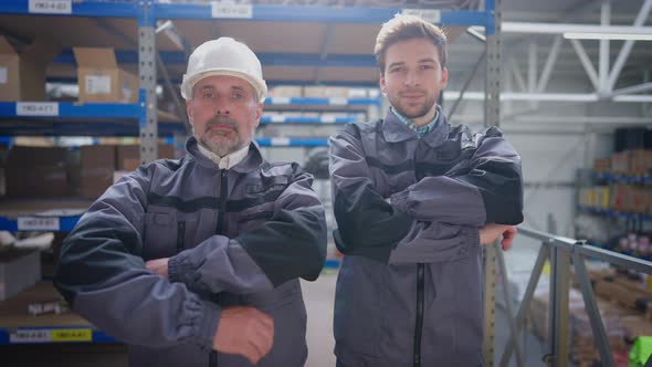 Two Confident Professional Warehouse Workers Crossing Hands Smiling Looking at Camera alt