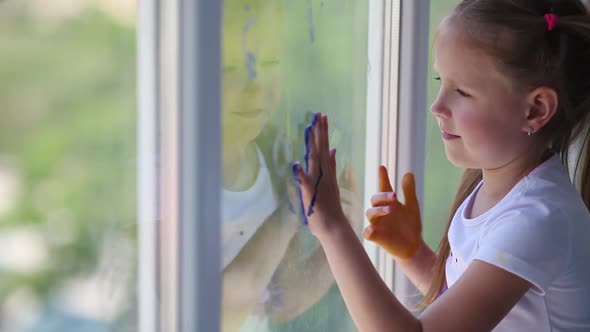 Children girl draw with palms on the window.