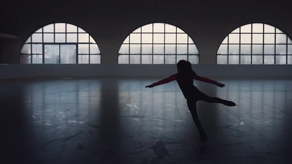 Little Girl Skater Glides on Skates on a Dark Ice Arena alt
