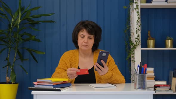 Middle Aged Woman with Credit Card Using Smart Phone for Online Shopping